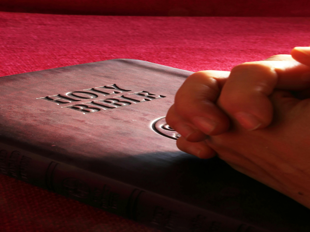 Praying hands on Holy Bible